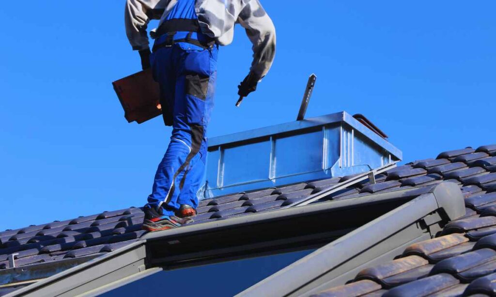 Roofing technician inspecting flashing and tile work around a chimney vent—an important step often included in Denver roofing estimates and repair quotes